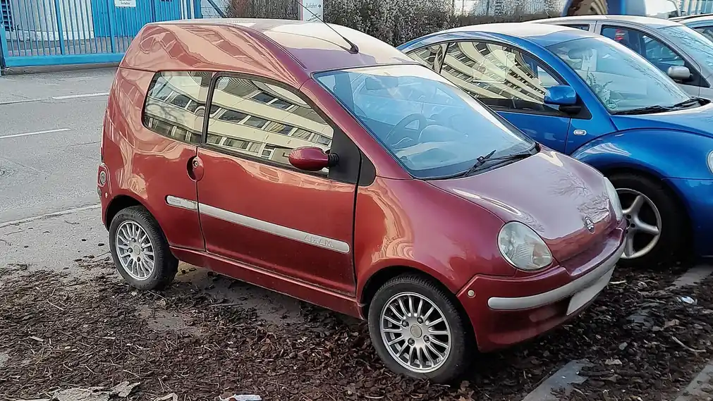 Voiturette rouge garée à côté d’une voiture